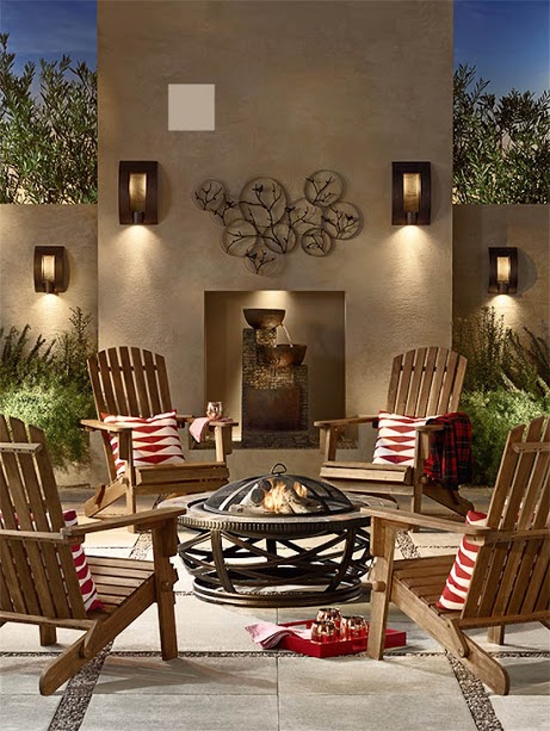 Outdoor seating set, four Adirondack chairs surrounding an outdoor firepit. Outdoor nighttime scene with four acacia wood Adirondack chairs with red-and-white patterned pillows and an outdoor fire pit.