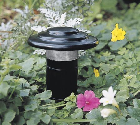 A landscape light in a flower bed.