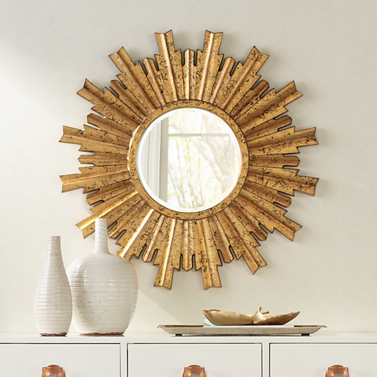A traditional gold sunburst mirror over a contemporary white console table with gold hardware.