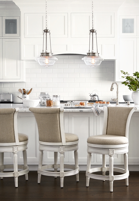 Two industrial-style clear glass pendant lights hanging above a kitchen stand.