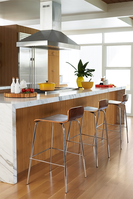 Modern minimalist barstools lined up against a kitchen bar area.