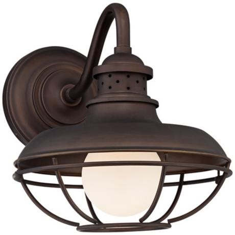 Dark bronze finish metal outdoor wall light, with a caged design that shows a luminous globe bulb.