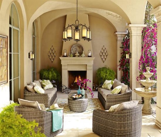 Yellow stone veranda, fully decorated with outdoor furniture, a chandelier, and fountain.
