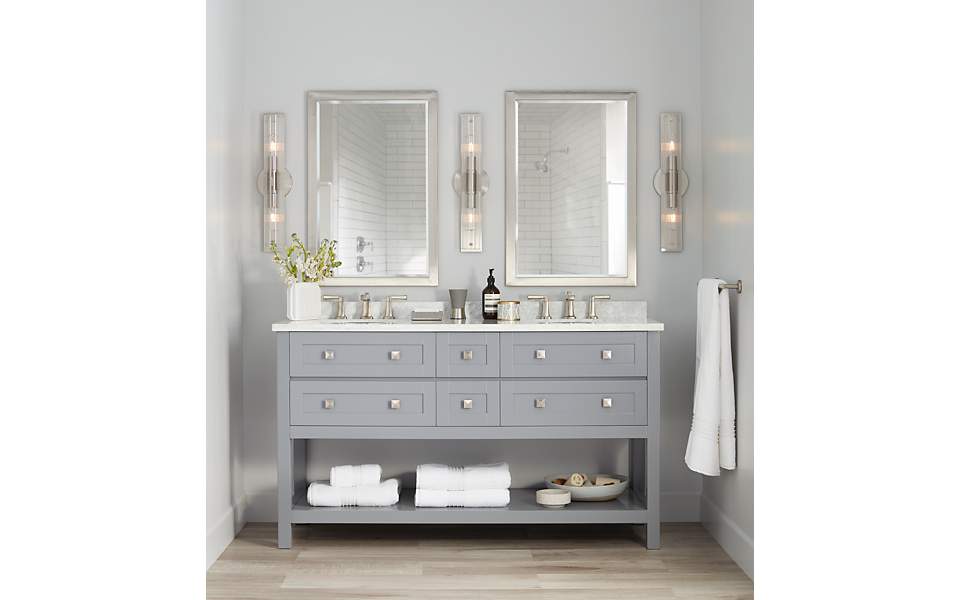 A vanity with two sinks and two mirrors with three wall sconces. 