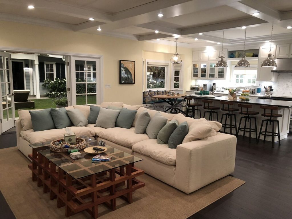 A clean-looking living room with a sectional sofa set and a kitchen visible in the background.